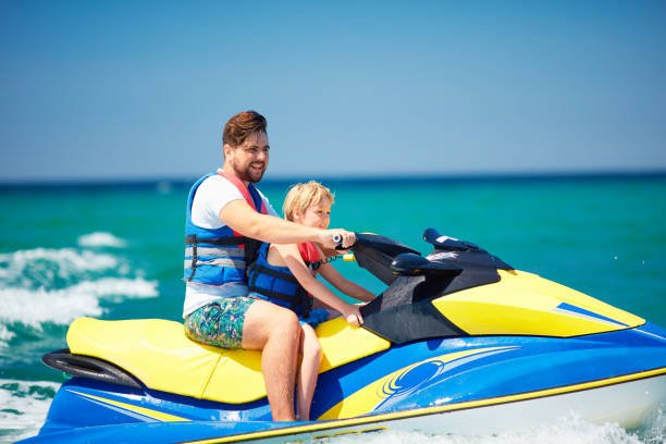 happy, excited family, father and son having fun on jet ski at summer vacation