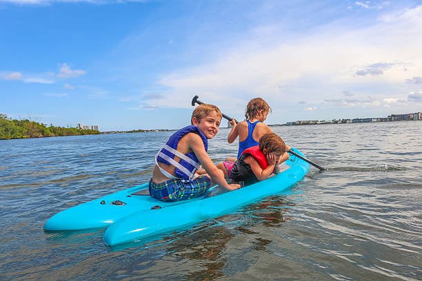 Three happy kids on a paddleboard in the ocean